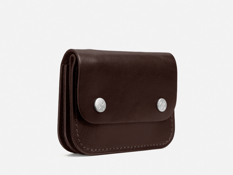 A dark brown leather wallet with rounded edges, featuring two silver snap buttons on the front flap, photographed against a plain white background.