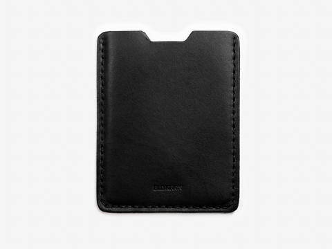 A minimalist black leather card holder with visible stitching along the edges, photographed against a plain white background.