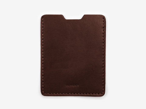 A slim, rectangular brown leather card holder with rounded corners, minimal stitching along the edges, and a small notch at the top center.