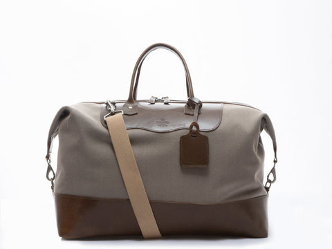 Beige and olive carryall bag with a tan strap on a white background