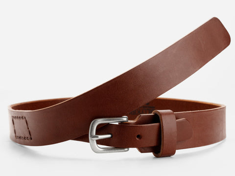 A brown leather belt with a silver buckle is displayed against a white background. The belt is coiled loosely, showing its smooth texture and stitched detail near the end.