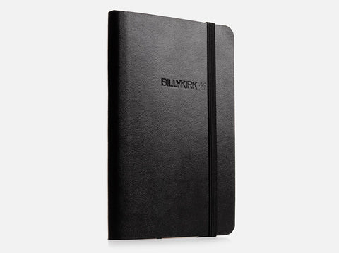 A black, hardcover notebook with rounded corners and an elastic band closure, featuring the word BILLYKIRK embossed on the front cover, photographed against a plain white background.