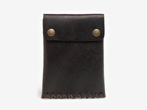 A dark brown leather pouch with visible stitching at the bottom and two brass snap buttons on the flap, set against a plain white background.