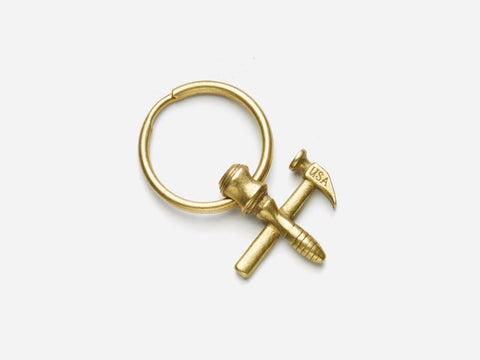 A gold keyring featuring three small charms shaped like a screw, a nail labeled USA, and a hex nut, crossed over each other on a white background.