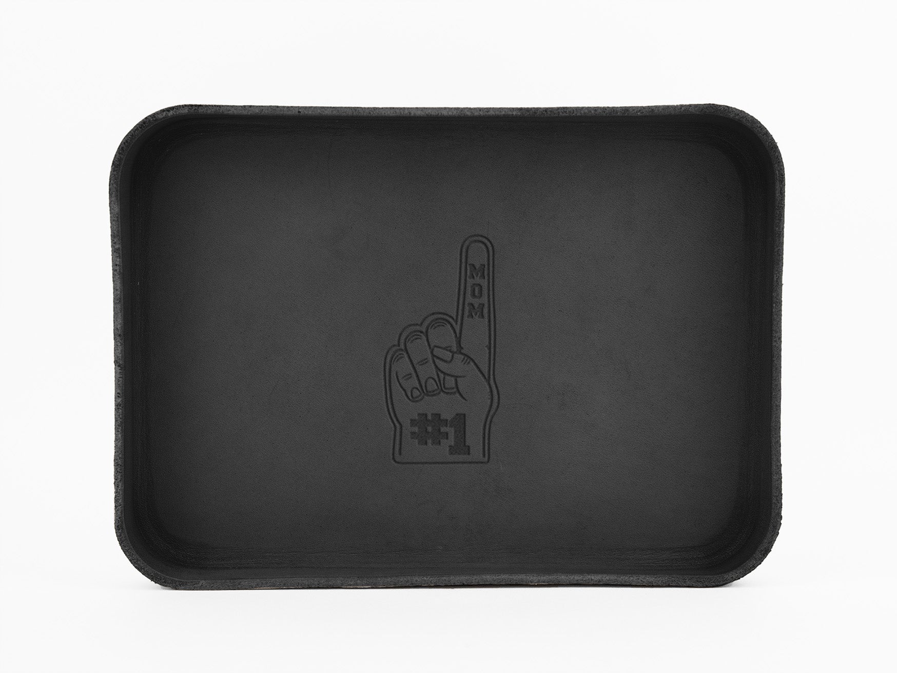 A rectangular black tray with an illustration of a foam finger in the center, displaying an upright index finger and the text MOM #1 written vertically and horizontally on the finger.