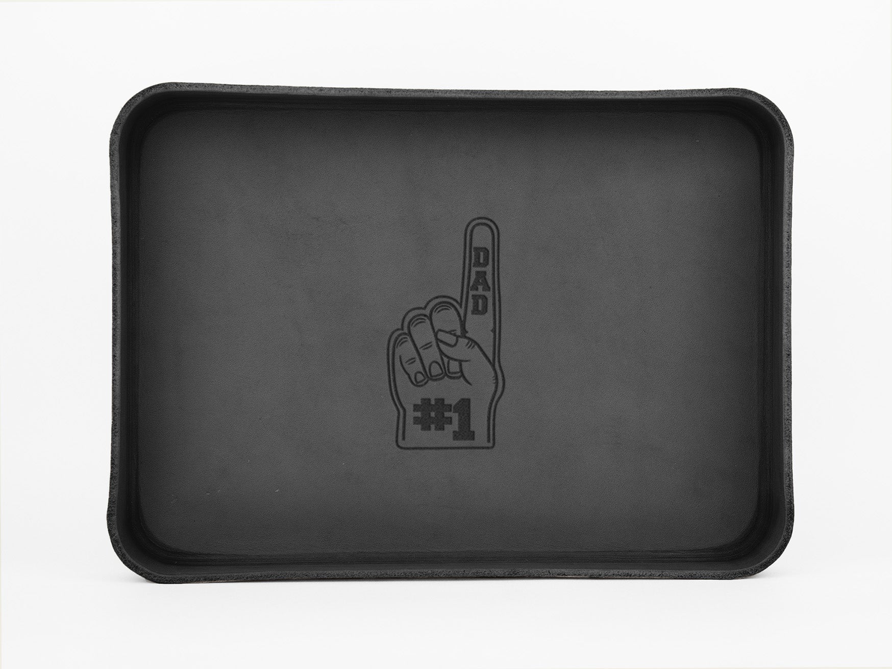 A rectangular black tray with an illustration of a foam finger in the center, labeled DAD on the finger and #1 at the base. The background of the tray is plain and unadorned.