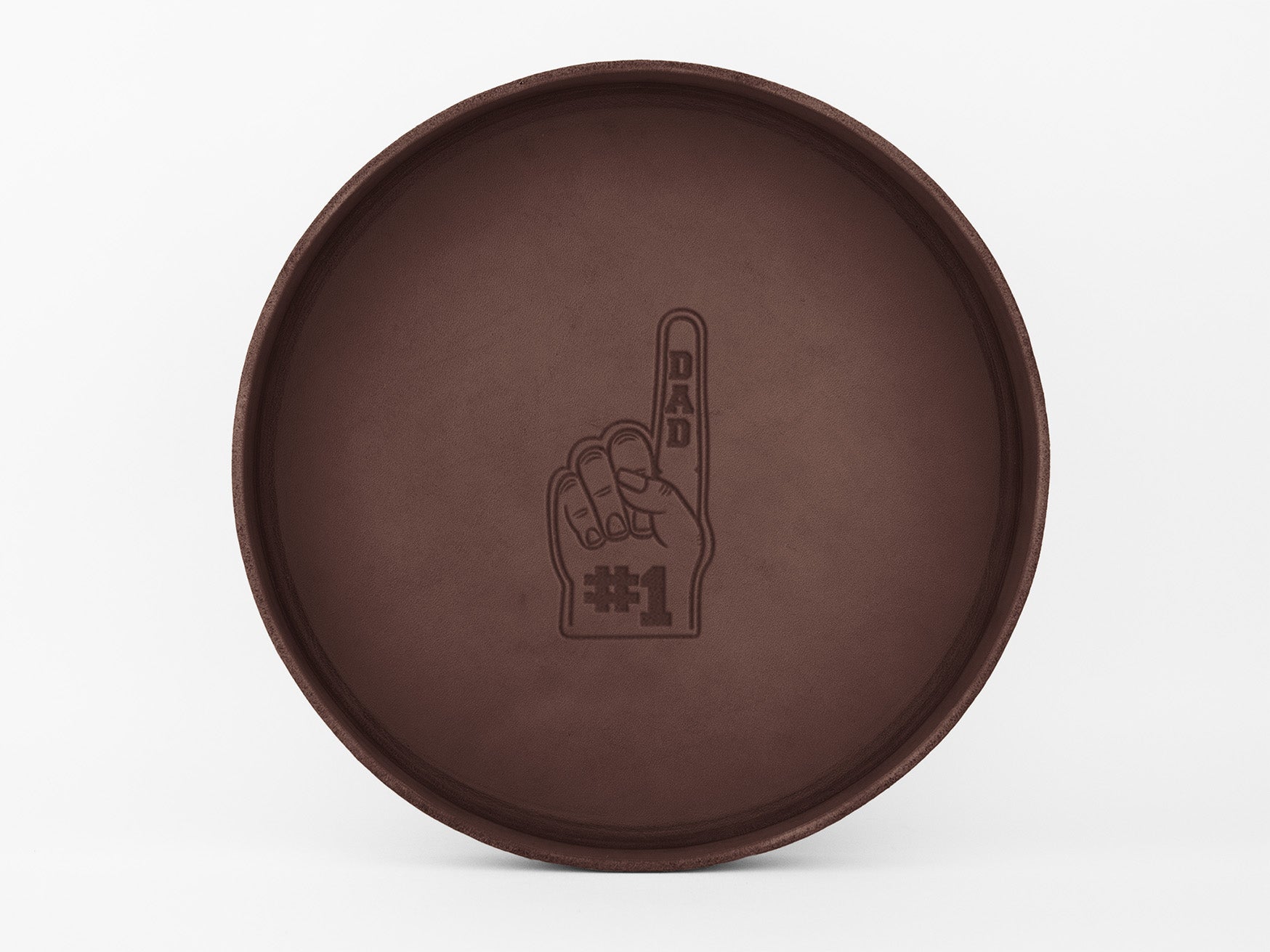 A round brown tray with an embossed image of a foam finger that reads “DAD” on the finger and “#1” on the palm, centered on the tray’s surface.