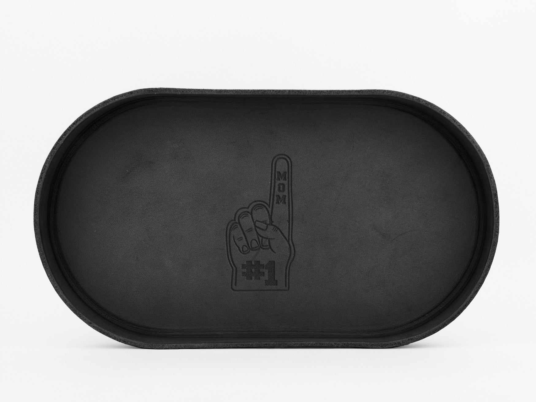 A black oval tray with an embossed design of a foam finger hand. The finger points upward and reads MOM with #1 at the base, all in black on the trays surface.