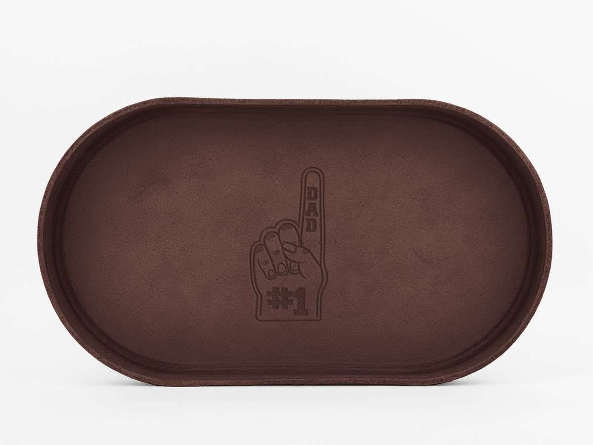 A brown oval tray with an embossed image of a foam finger showing DAD on the raised finger and #1 on the palm, set against a plain white background.