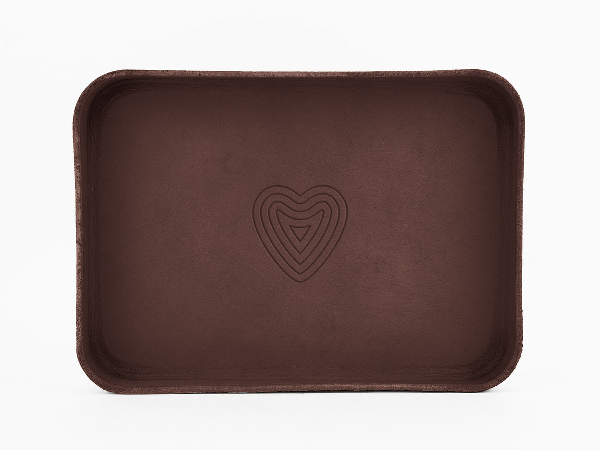 A rectangular, brown tray with rounded corners and a layered heart-shaped design embossed in the center, set against a plain white background.