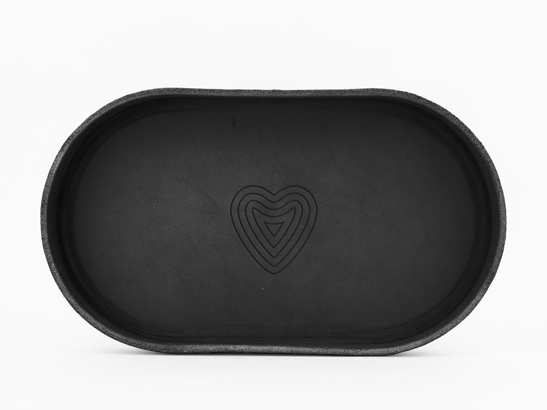 A black, oval-shaped tray with a subtle heart-shaped design engraved in the center, photographed against a plain white background.