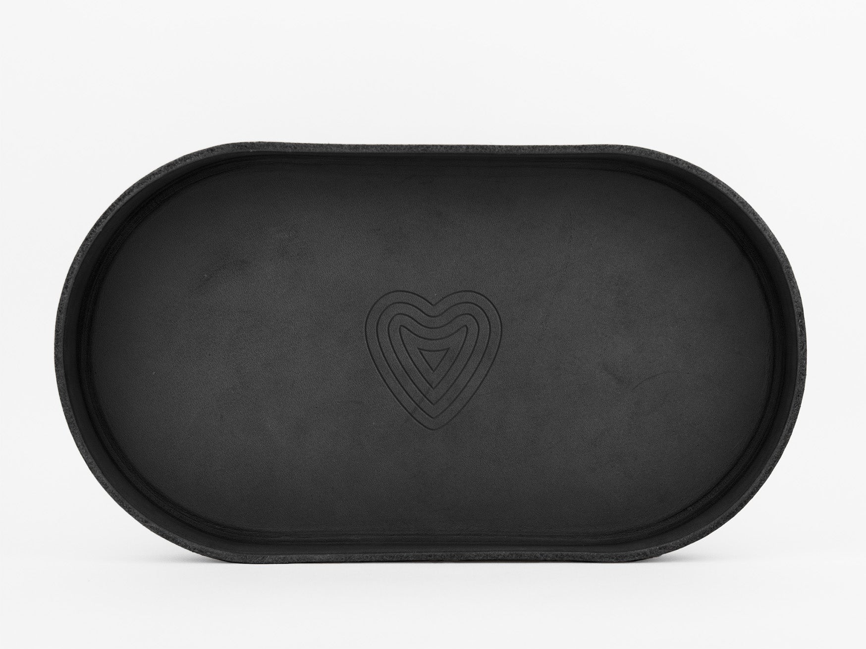 A black, oval-shaped tray with a raised edge and a simple heart-shaped line pattern in the center, set against a plain white background.