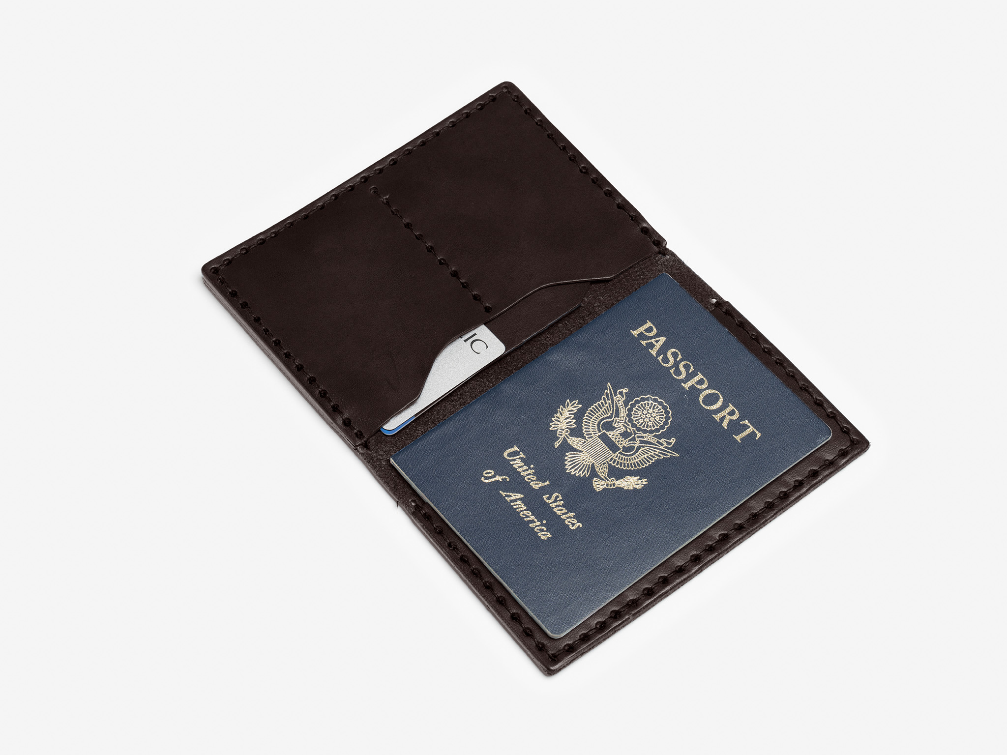 A brown leather wallet holds a blue United States passport and a metal tool or card on a white background.