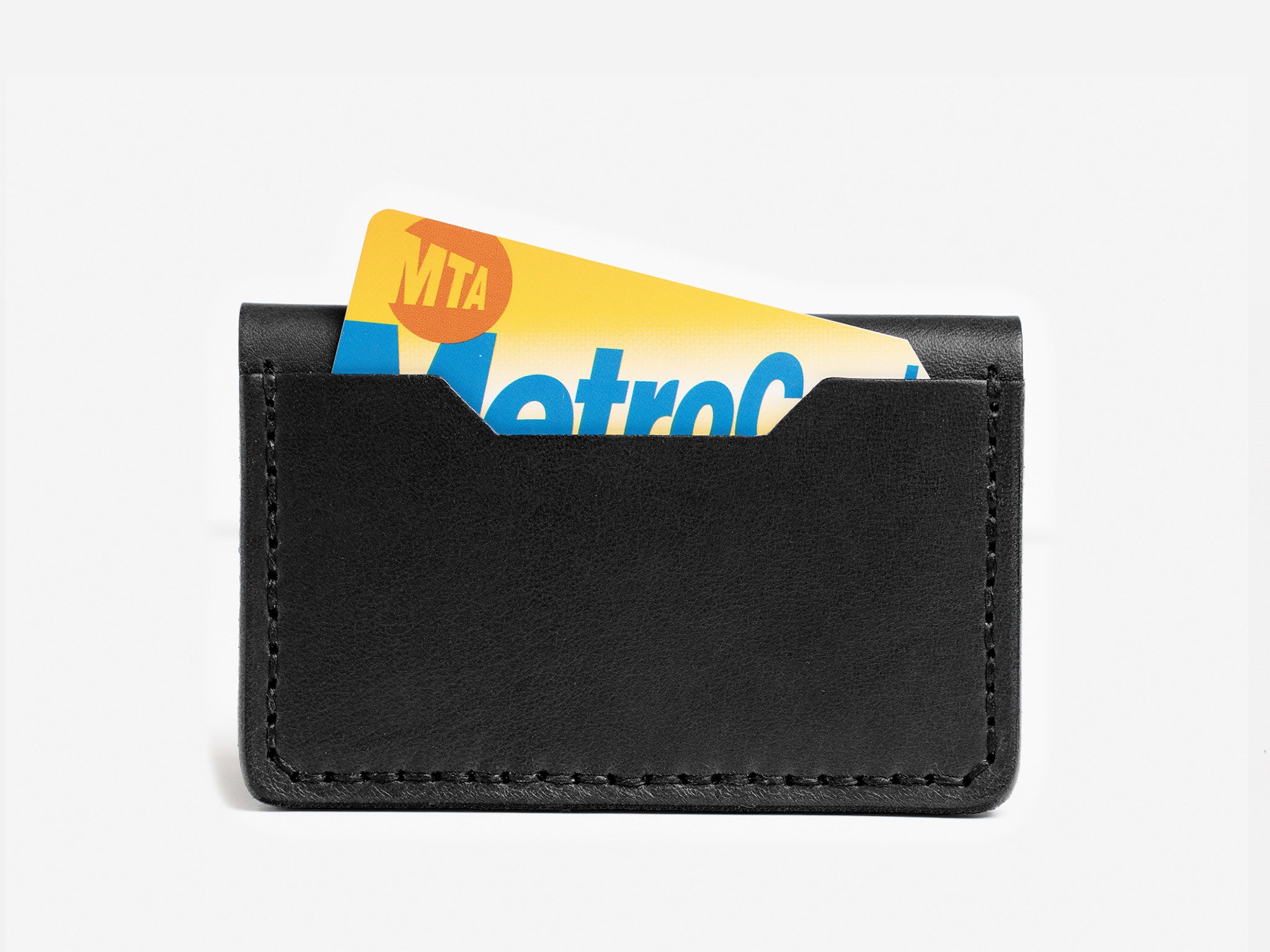 A black leather card holder with a partially visible yellow and blue MTA MetroCard sticking out against a plain white background.