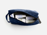 Navy blue toiletry bag with travel-sized products on a white background