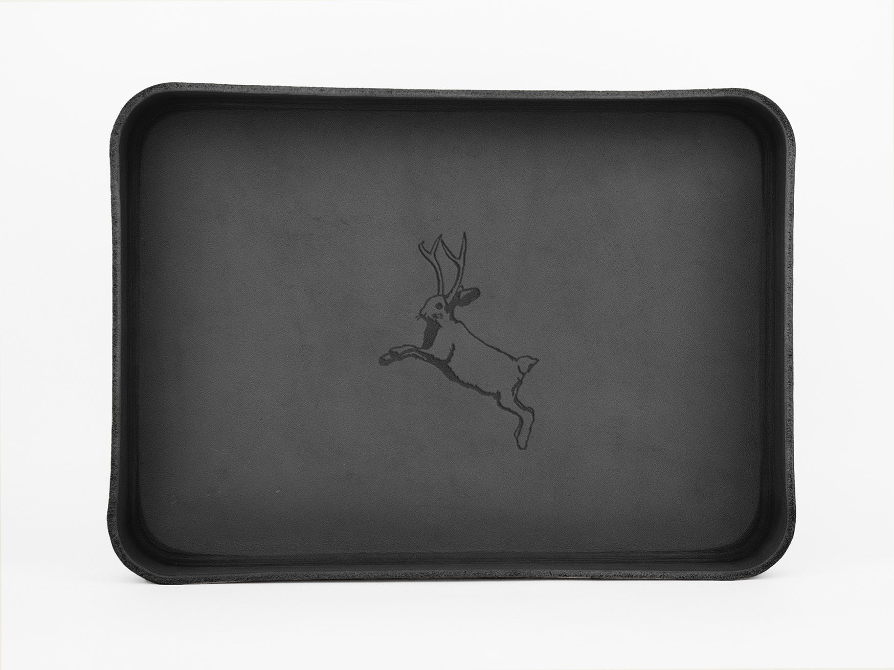 A black rectangular tray with raised edges features a simple line drawing of a jackalope, a mythical rabbit with antlers, in the center against a plain background.