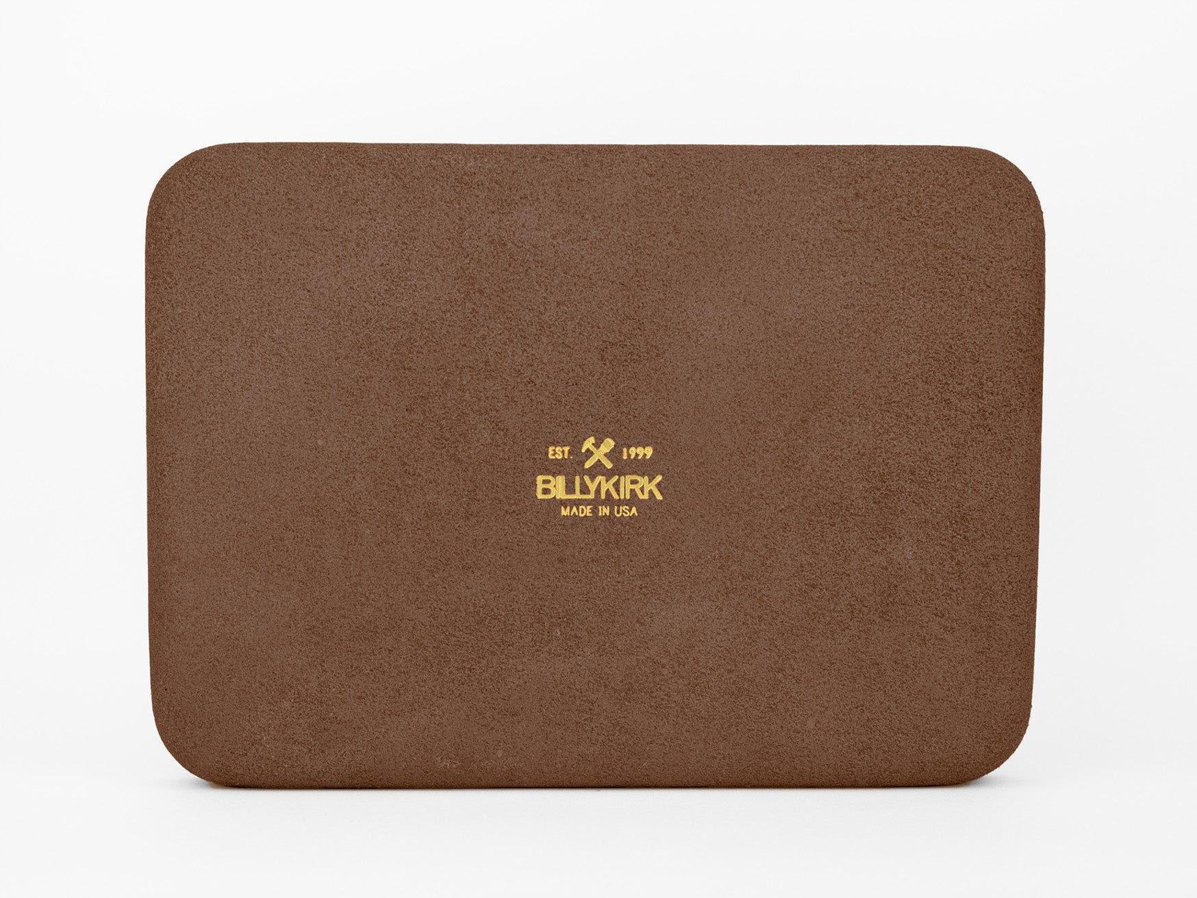 A rectangular brown leather pad with rounded corners features gold embossed text and logo in the center that reads, EST. 1999 BILLYKIRK MADE IN USA, on a plain white background.