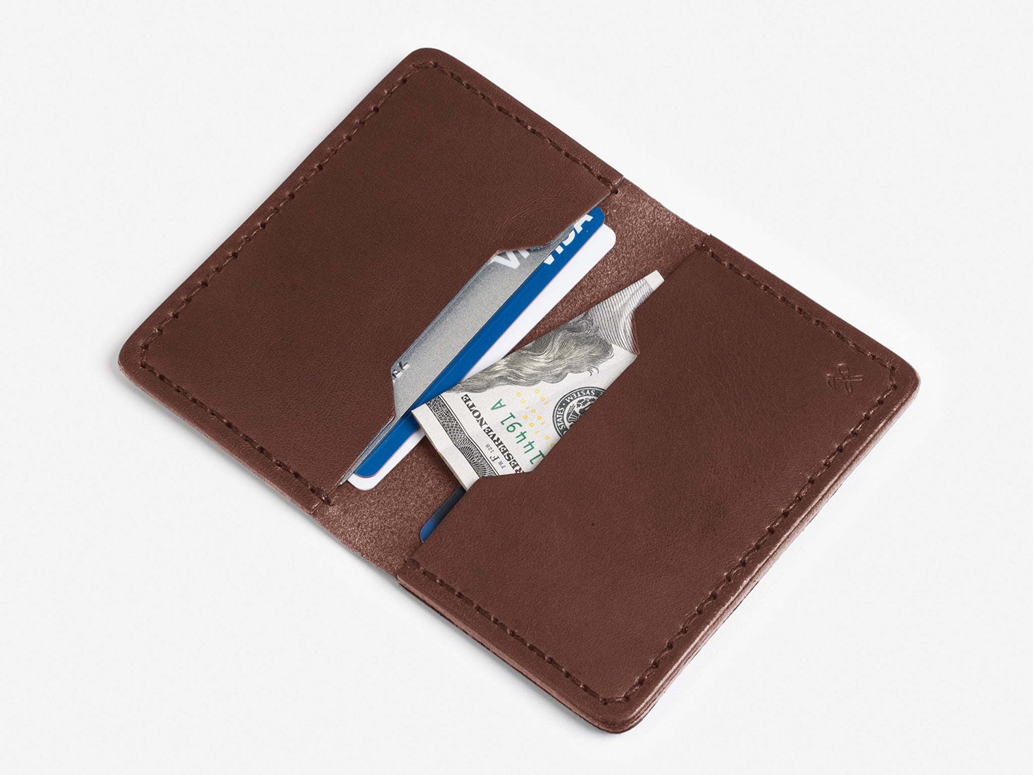 A brown leather wallet open to show a folded U.S. $100 bill and two credit cards inside its pockets, on a white background.