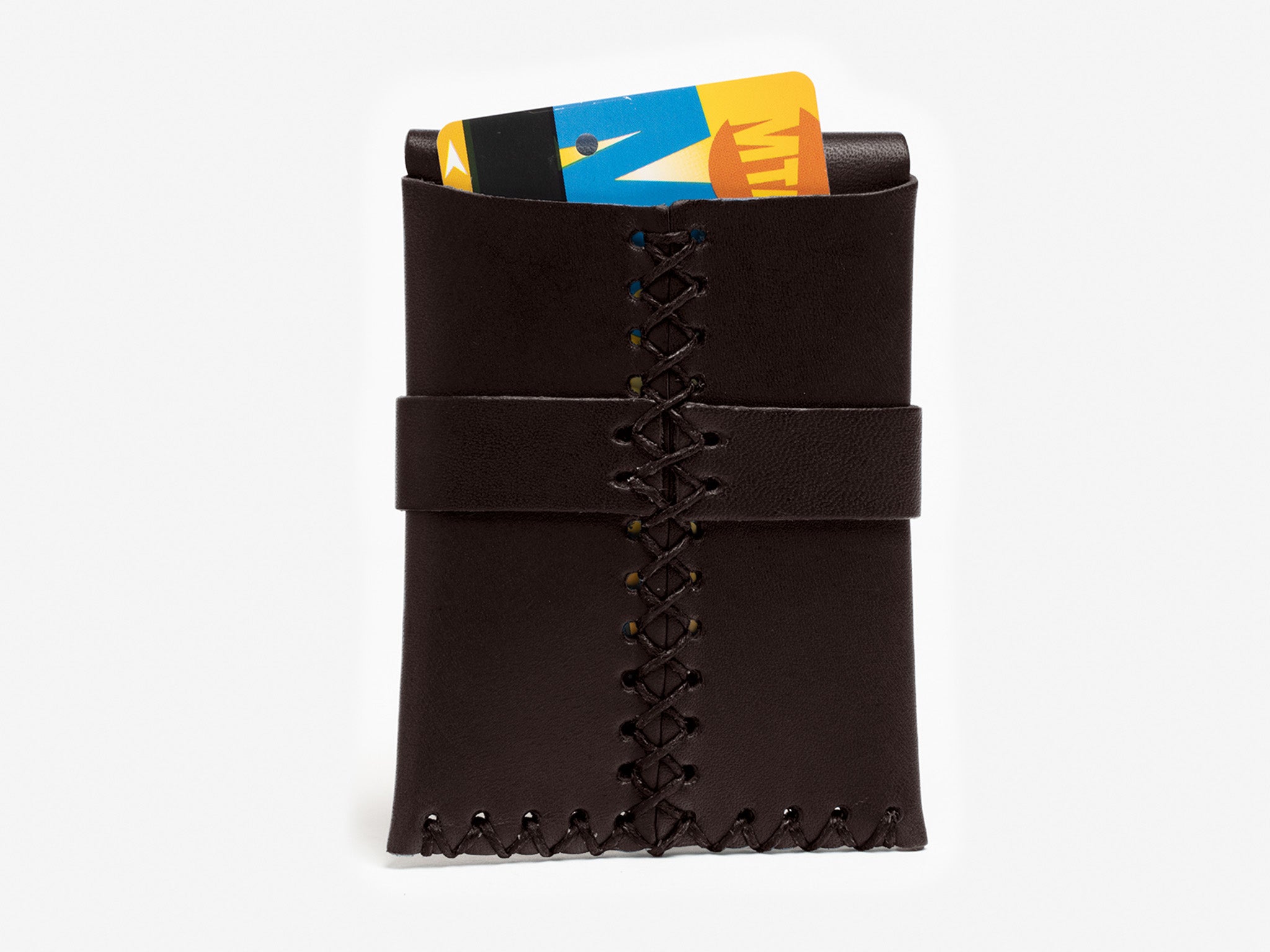 A dark brown leather wallet with visible stitching holds a New York City MetroCard,  partially sticking out of the rear wallet on a white background.