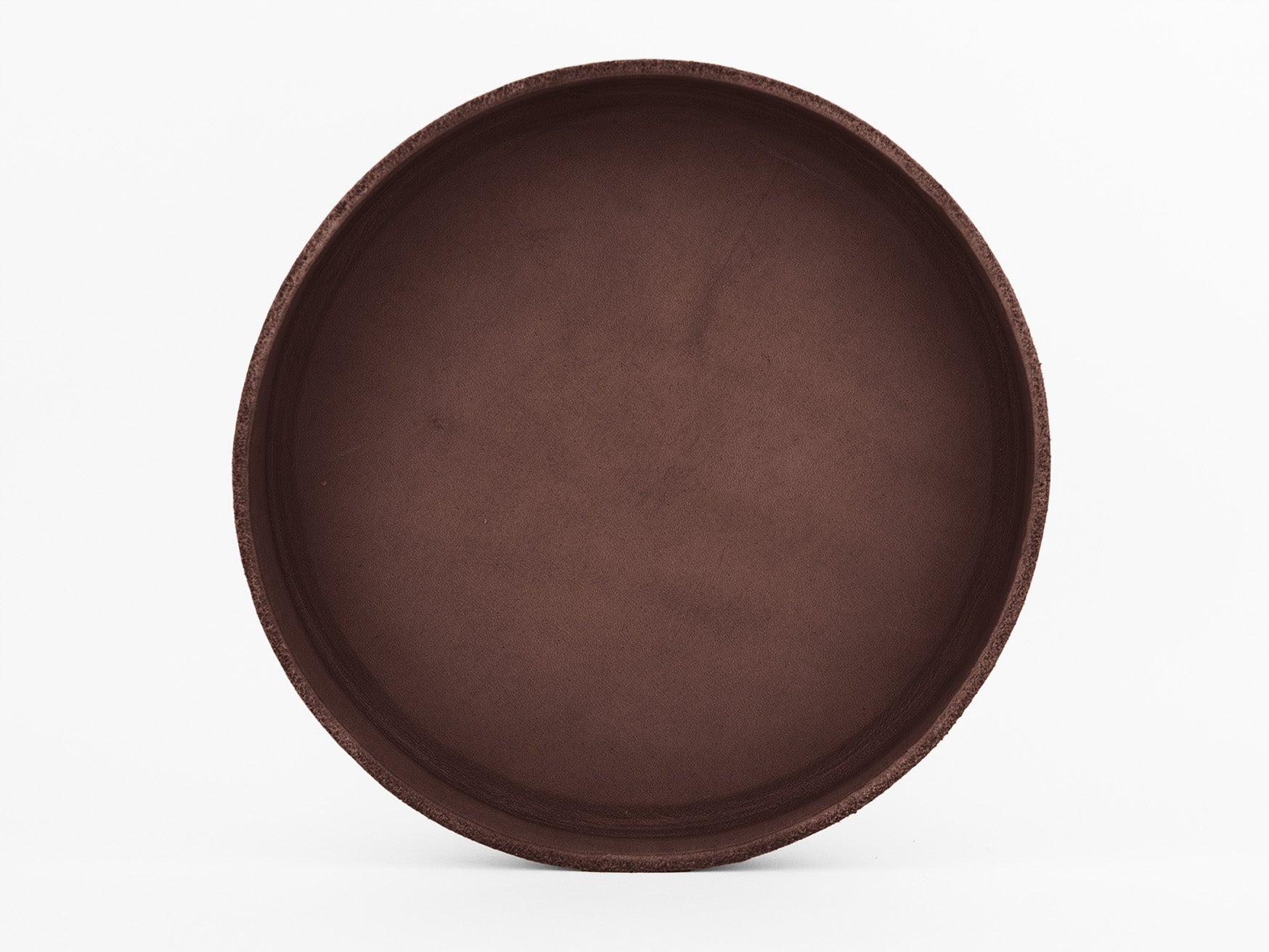 A round, shallow, empty brown tray or plate with a smooth surface and slight texture along the rim, photographed from above against a white background.