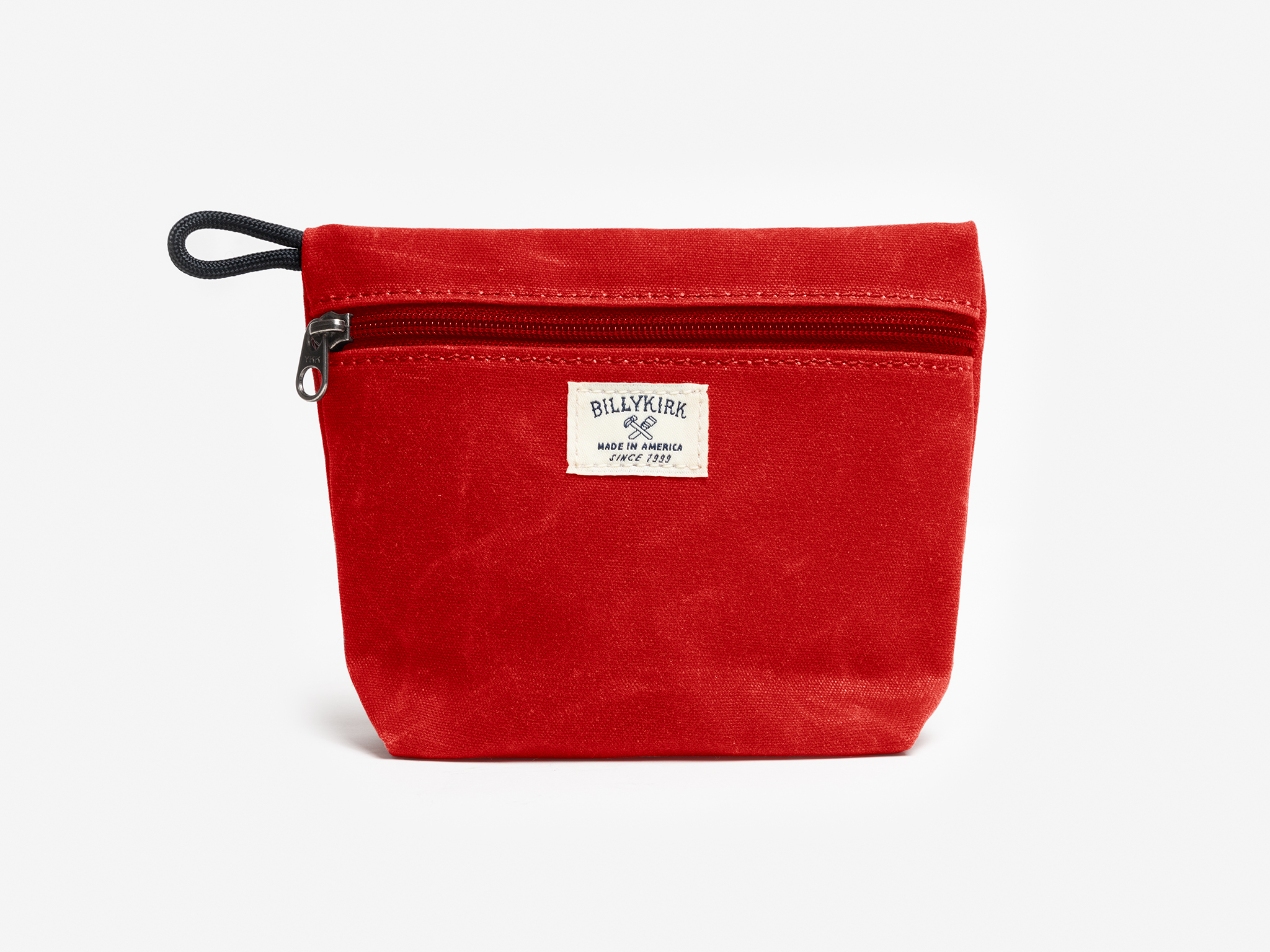 A red waxed canvas pouch with zipper closure on a neutral background. It features a cream woven tag that reads "Billykirk made in america since 1999".