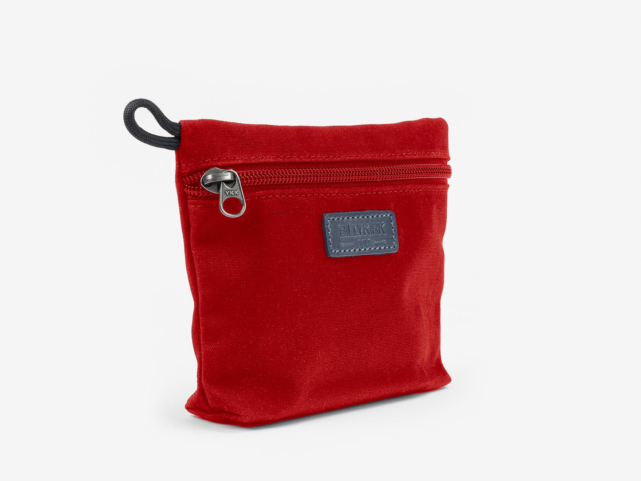 A small, red zippered pouch with a black zipper pull and a rectangular black patch on the front, standing upright against a plain white background.