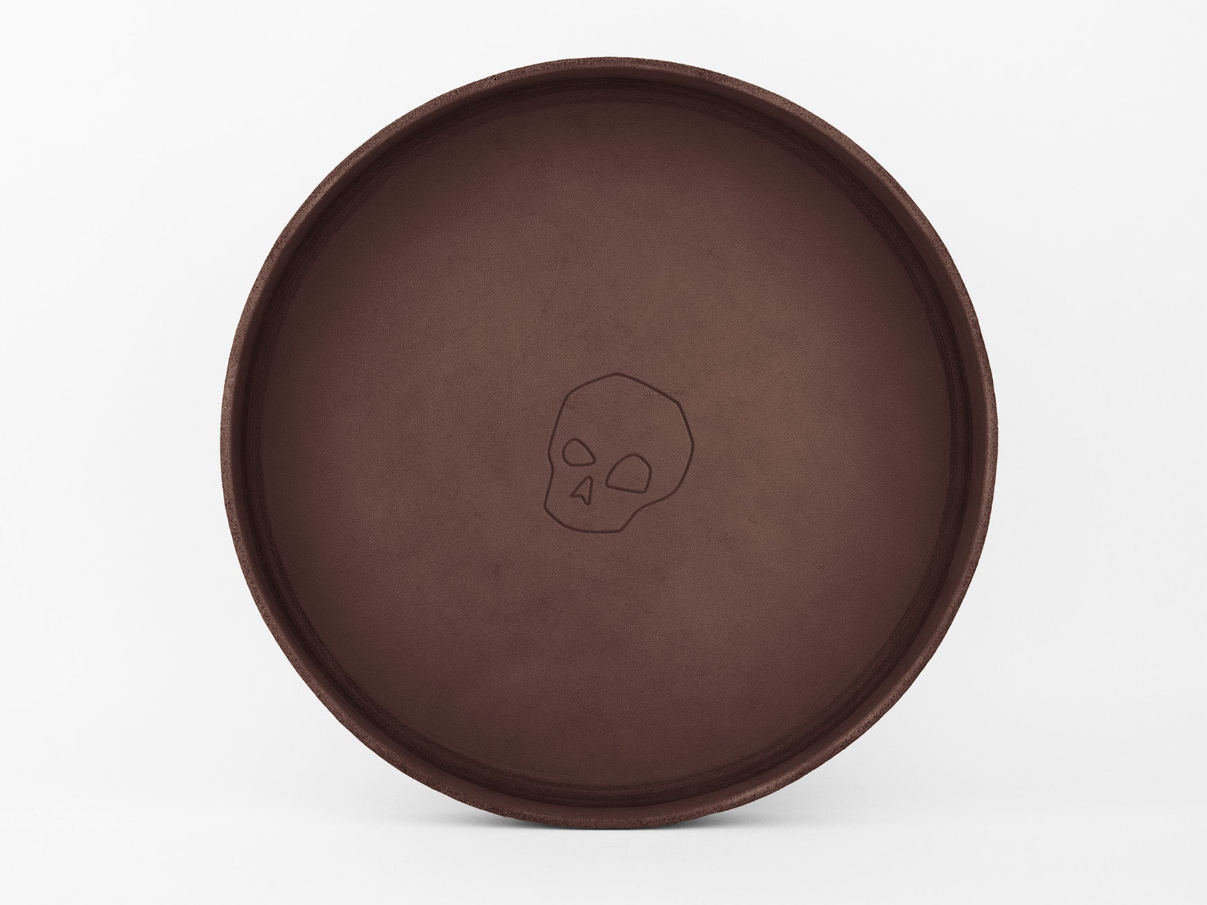 A round, brown tray with a simple outline of a skull design at the center, set against a plain white background.