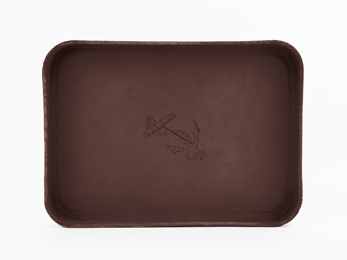 A rectangular, dark brown tray with slightly curved edges and an engraved anchor design in the center, set against a plain white background.