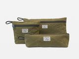 Three different sized olive waxed canvas pouches with zipper closures arranged together on a neutral background.
