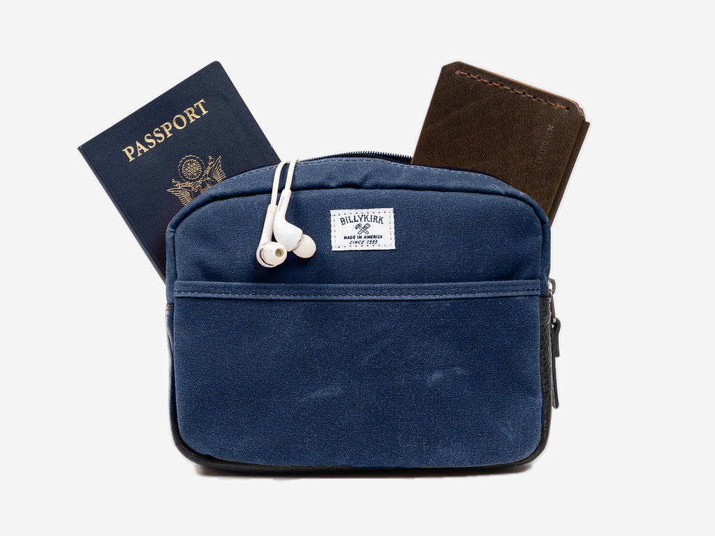 Blue travel pouch with passport, wallet, and earbuds on a white background