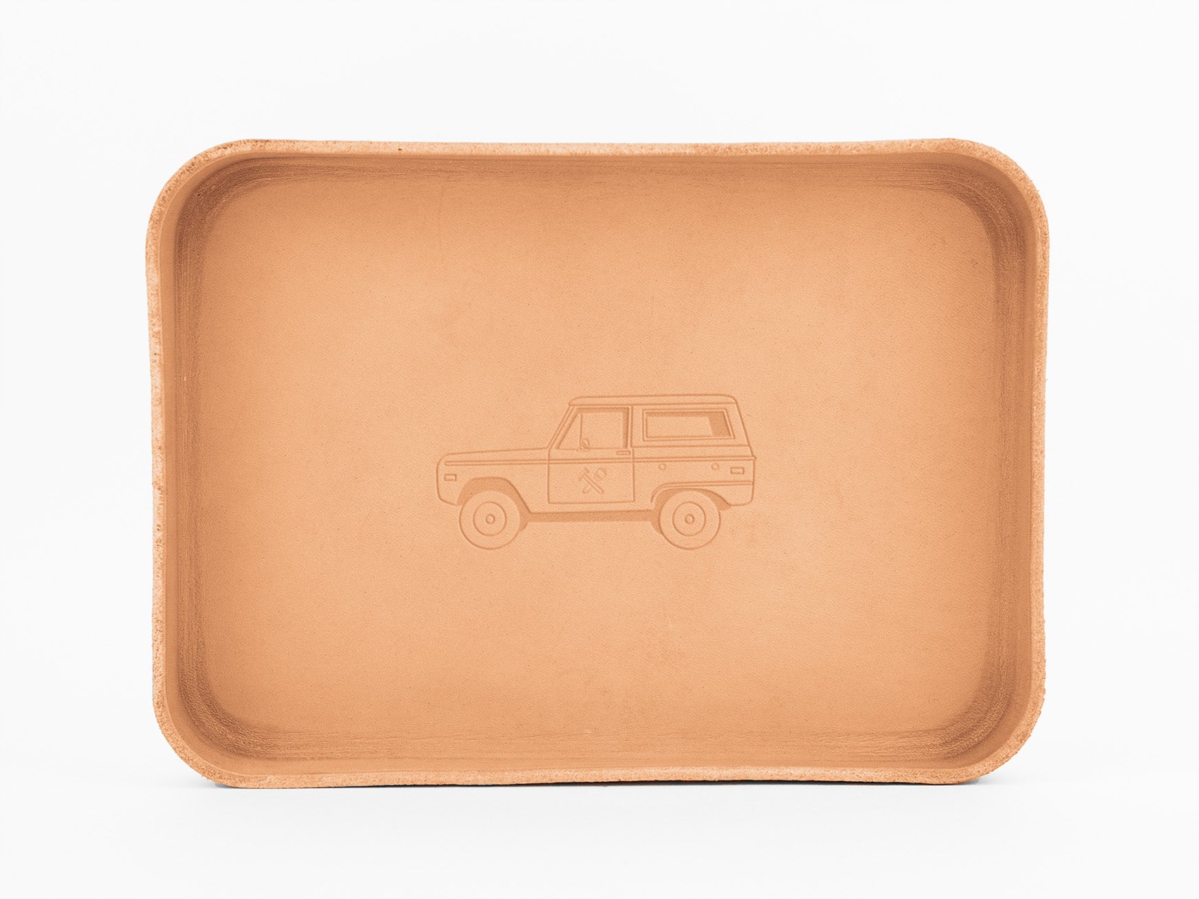 A rectangular, tan leather tray with rounded edges features an embossed outline of a classic SUV with a roof rack in the center. The tray is photographed on a plain white background.