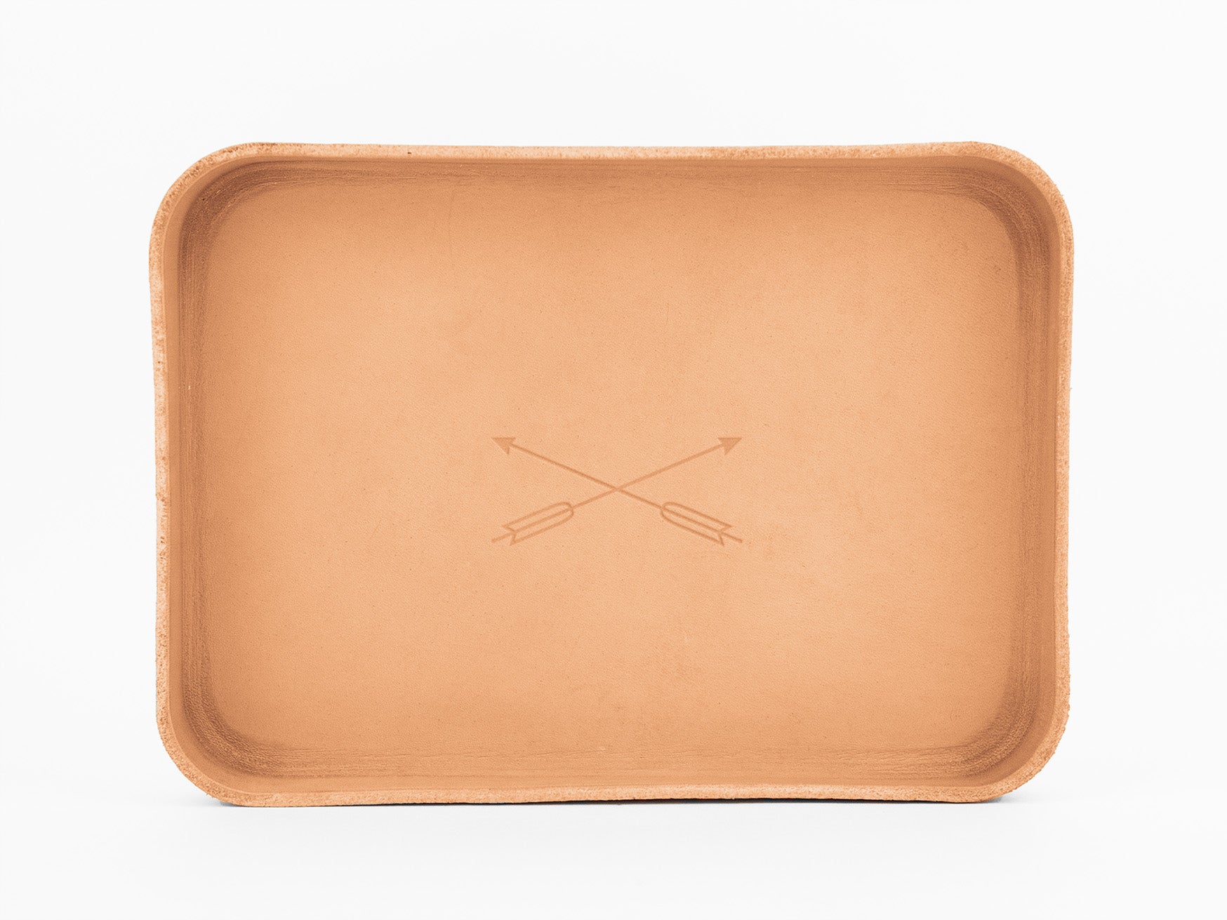 A rectangular tan leather tray with slightly raised edges and two crossed arrows engraved in the center, set against a plain white background.