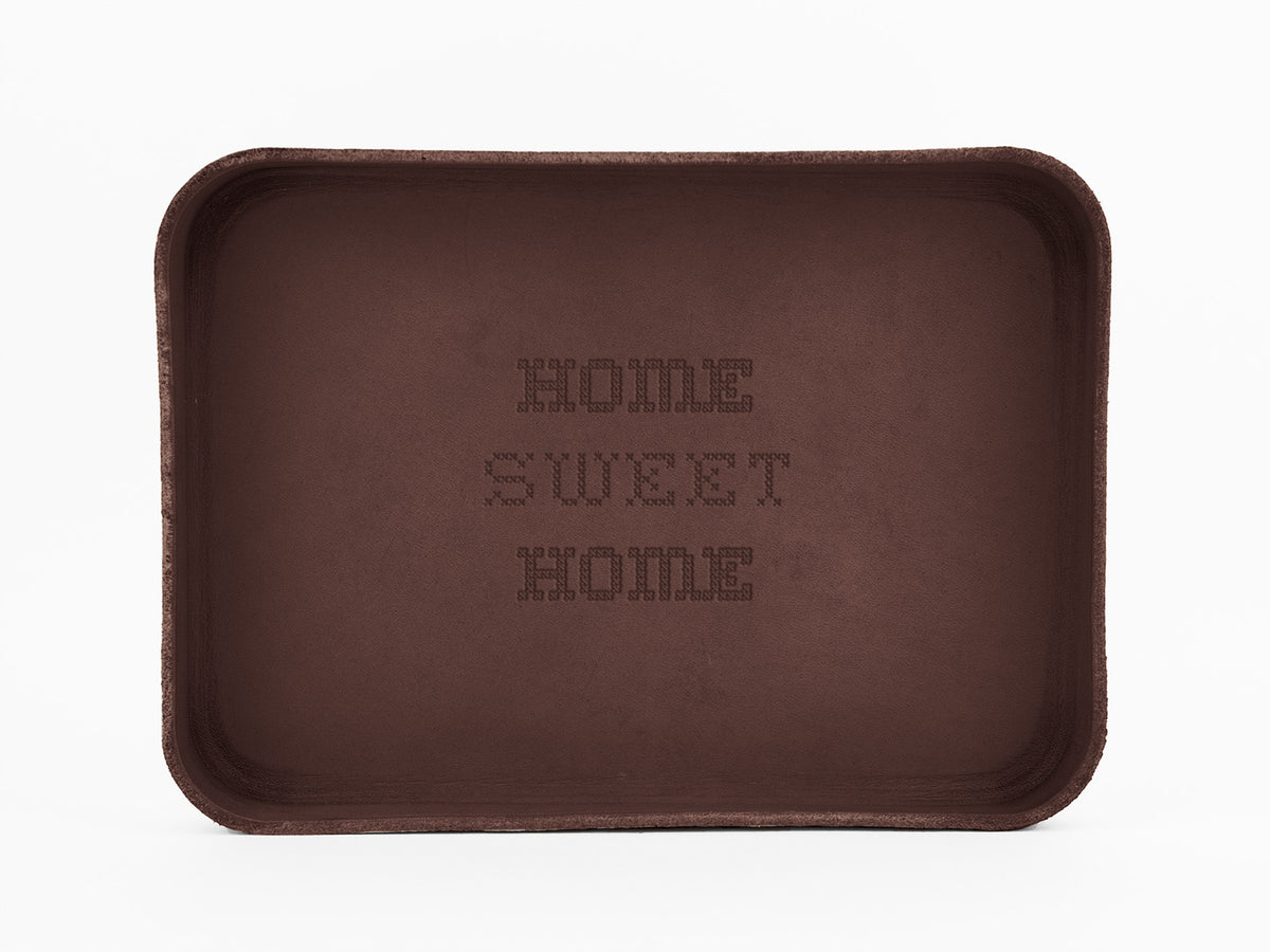 A rectangular brown tray with the words HOME SWEET HOME embossed in the center, displayed against a plain white background.