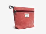 A nantucket red canvas pouch with zipper closure on a neutral background. It features a cream woven tag that reads "Billykirk made in america since 1999".