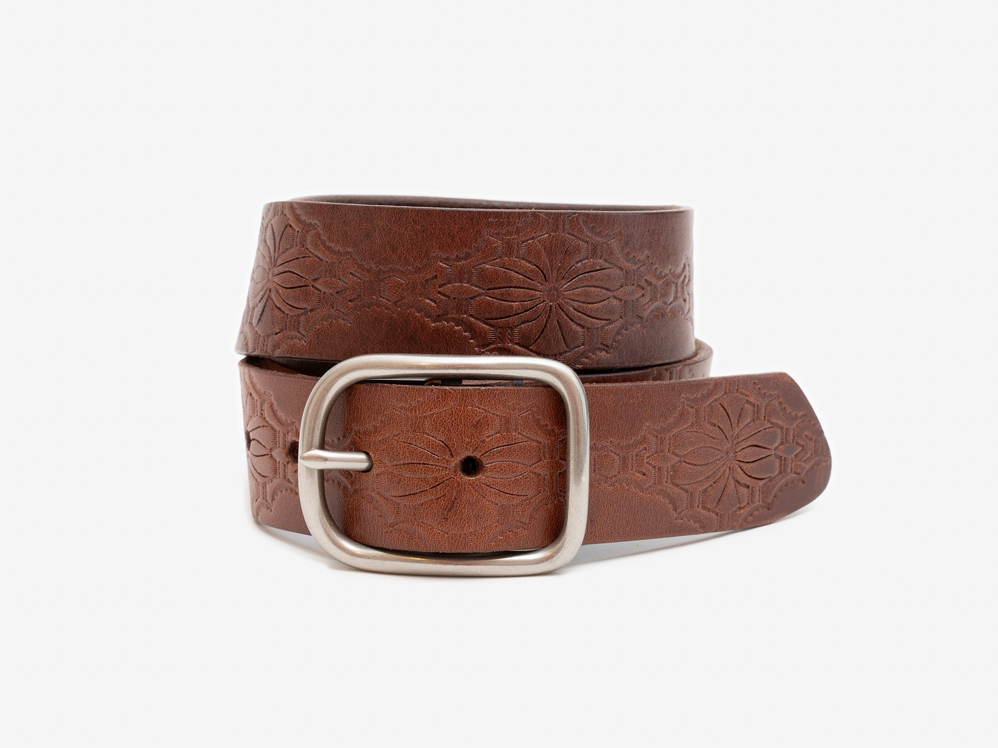 Brown leather belt with floral embossing and silver buckle on a white background