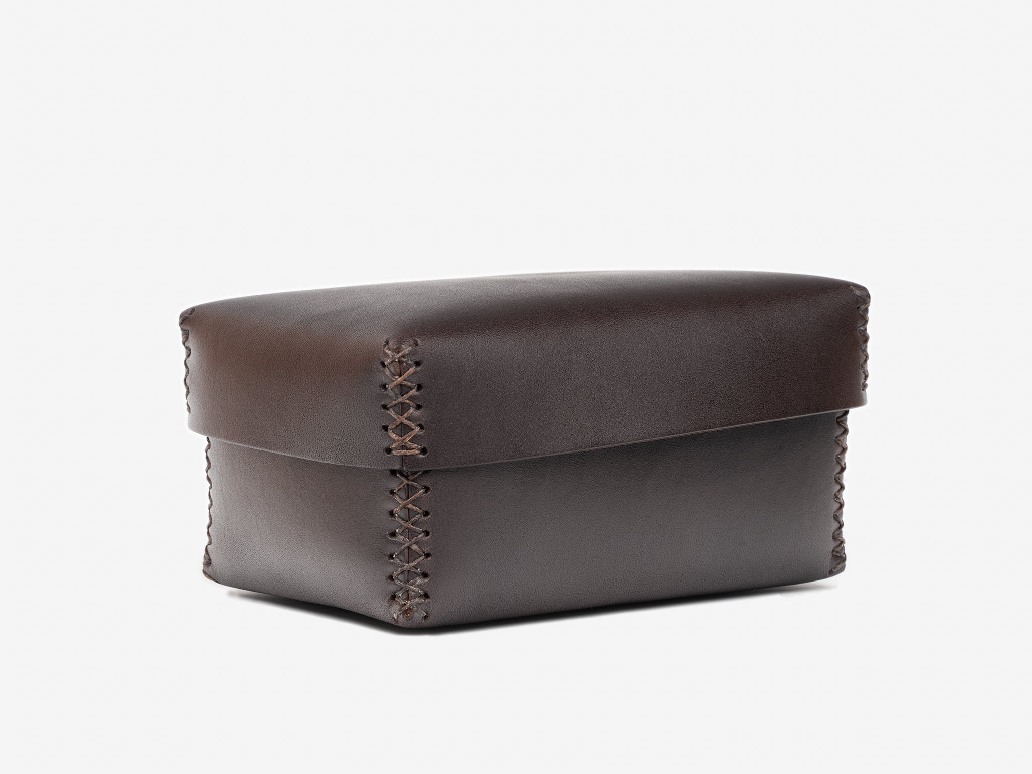 A small, rectangular, dark brown leather box with a stitched seam along the edges, shown closed against a plain white background.