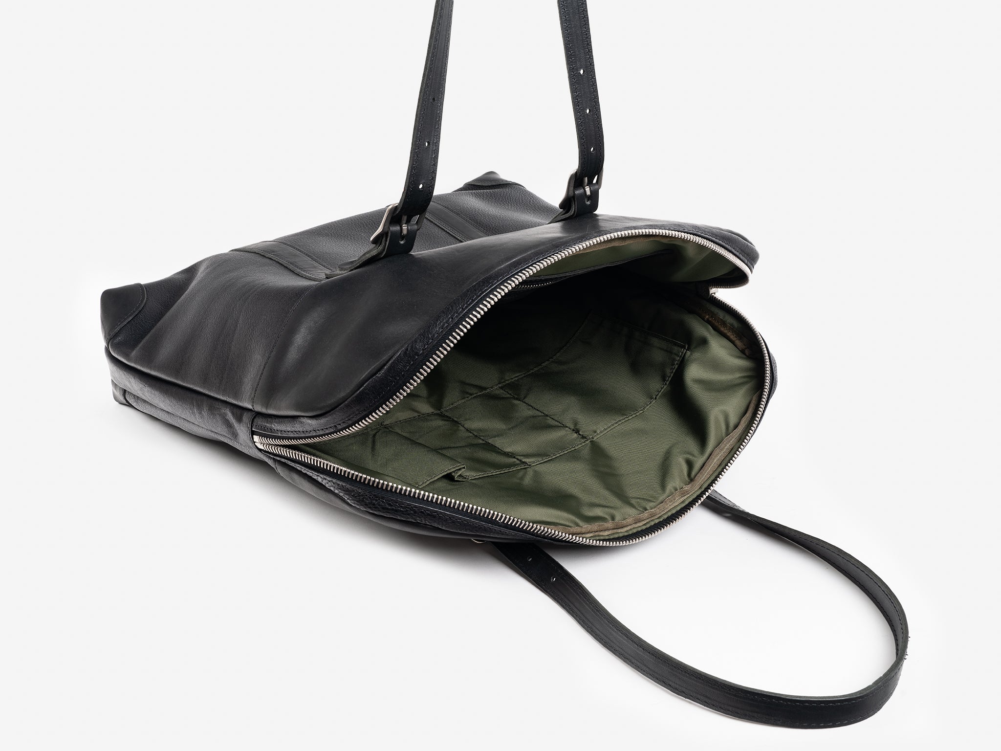 A black leather shoulder bag with black straps is unzipped, revealing an olive green fabric interior with several stitched pockets, set against a white background.