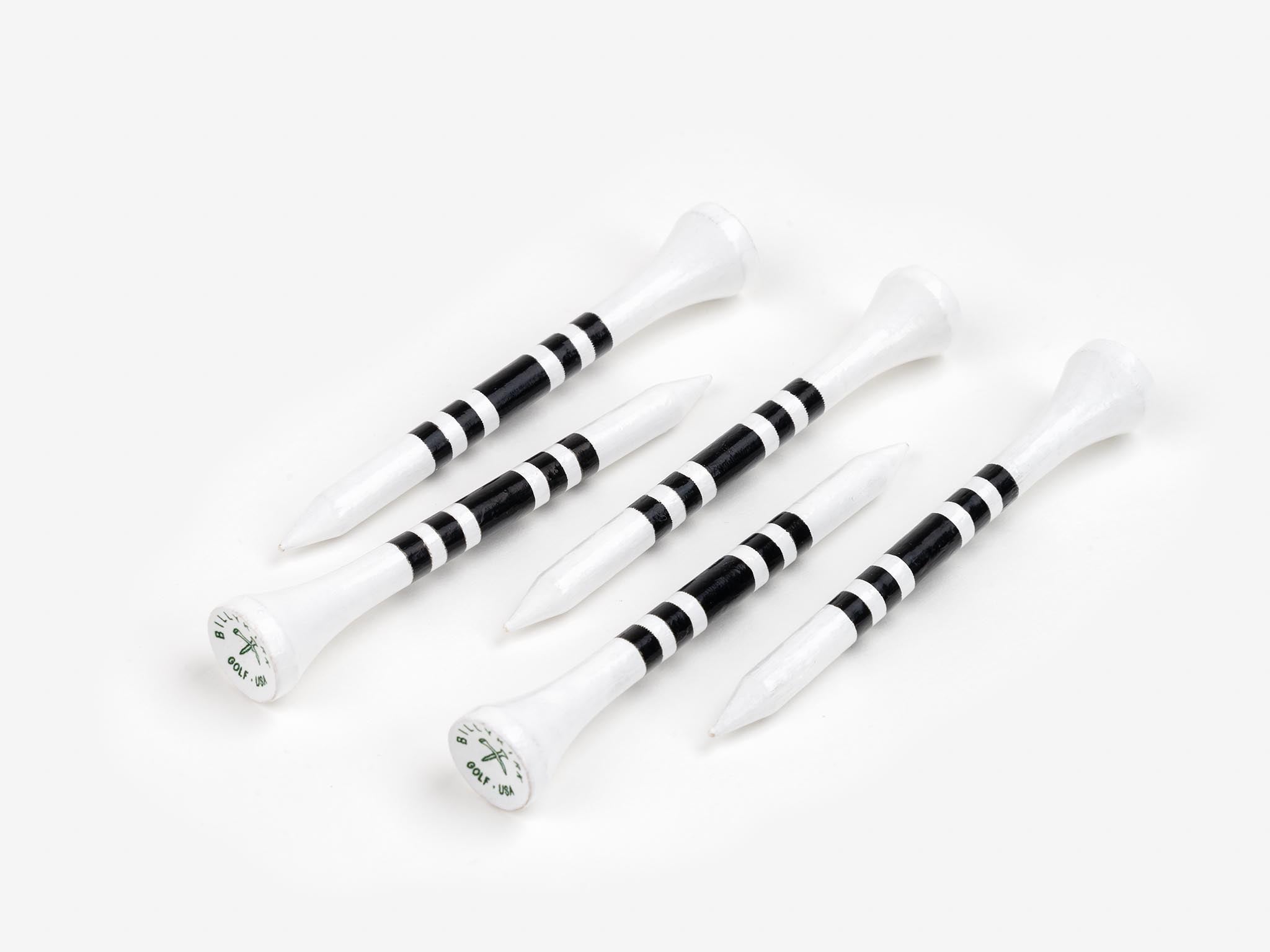 Five white golf tees with black stripes are arranged diagonally on a white surface. Each tee has a flat, circular top with a small logo or writing on it.