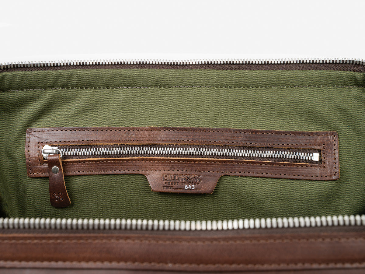 The image shows the inside of a bag with a green fabric lining, a Brown leather zippered pocket, and a visible zipper. A patch below the zipper reads BILLYKIRK with the number 643 beneath it.
