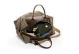 Taupe wool and olive leather carryall duffel bag with an olive green toiletry bag and clothes inside on a white background