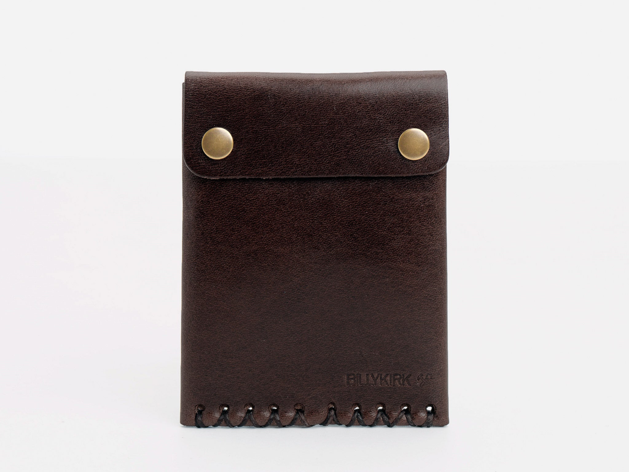 A dark brown leather wallet with a flap secured by two brass snap buttons, featuring stitched detailing at the bottom and the word BLVKRK embossed on the front.