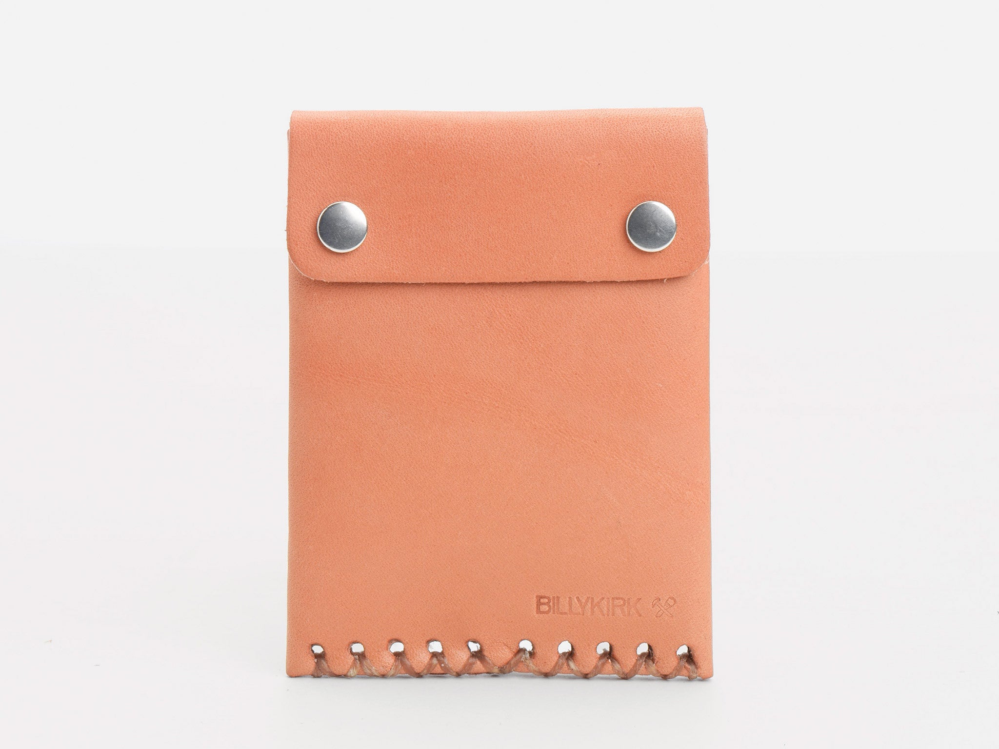 A tan leather wallet with two silver snap buttons and decorative stitching at the bottom, featuring the embossed logo BILLYKIRK in the lower right corner.