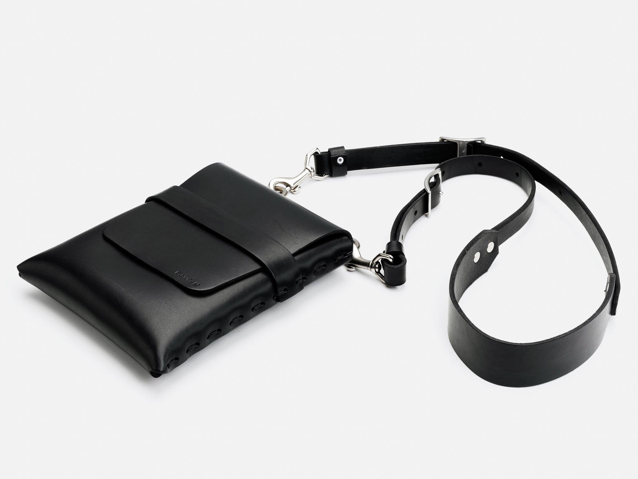 A sleek black leather crossbody bag with a front flap, silver hardware, and an adjustable shoulder strap, displayed on a white background.