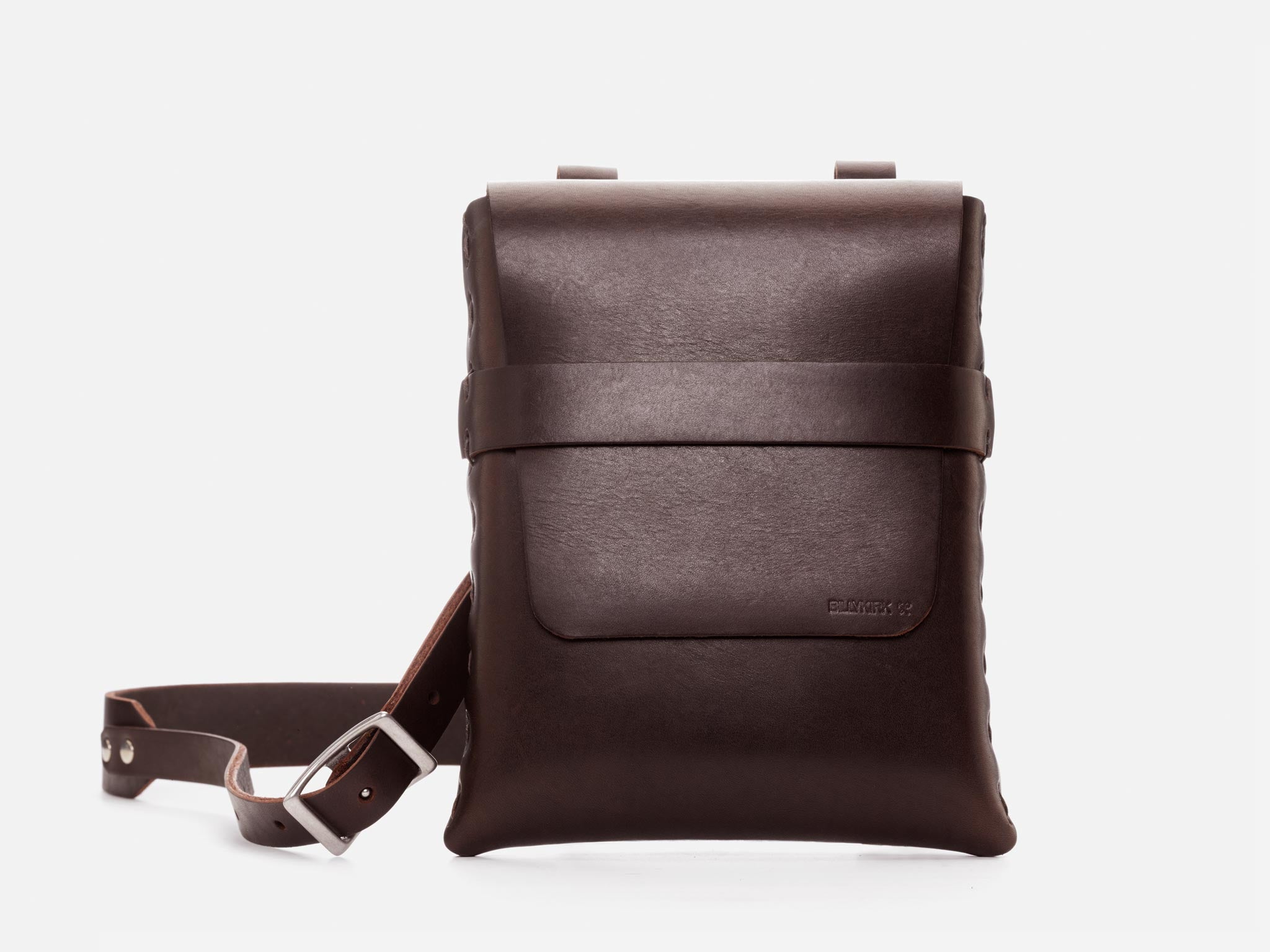A dark brown leather crossbody bag with a front pocket, strap, and silver buckle, displayed against a plain white background.