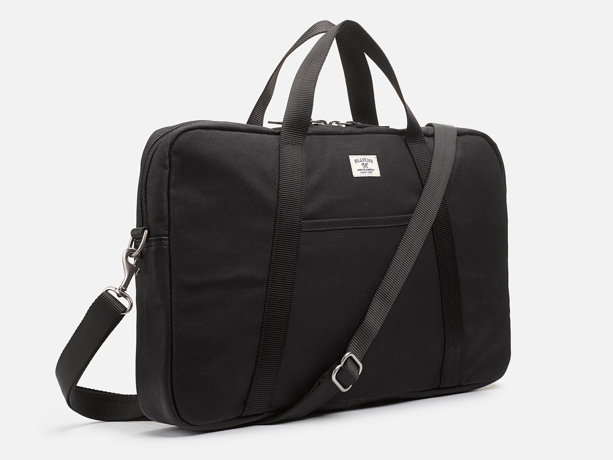 A black rectangular laptop bag with a top handle, front pocket, detachable shoulder strap, and a small white label on the front, against a plain white background.