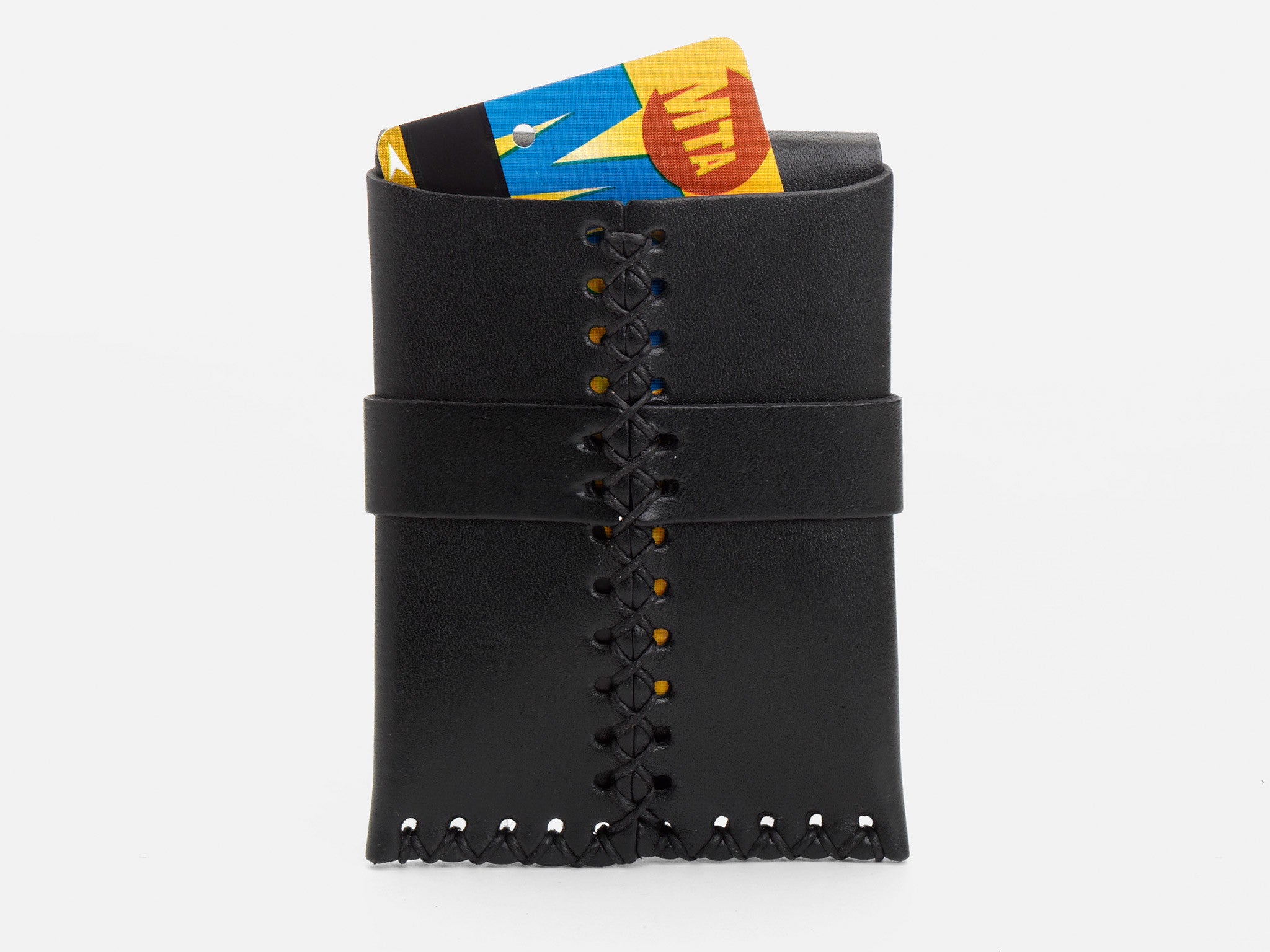 A black leather wallet with visible stitching holds a New York City MetroCard,  partially sticking out of the rear wallet on a white background.
