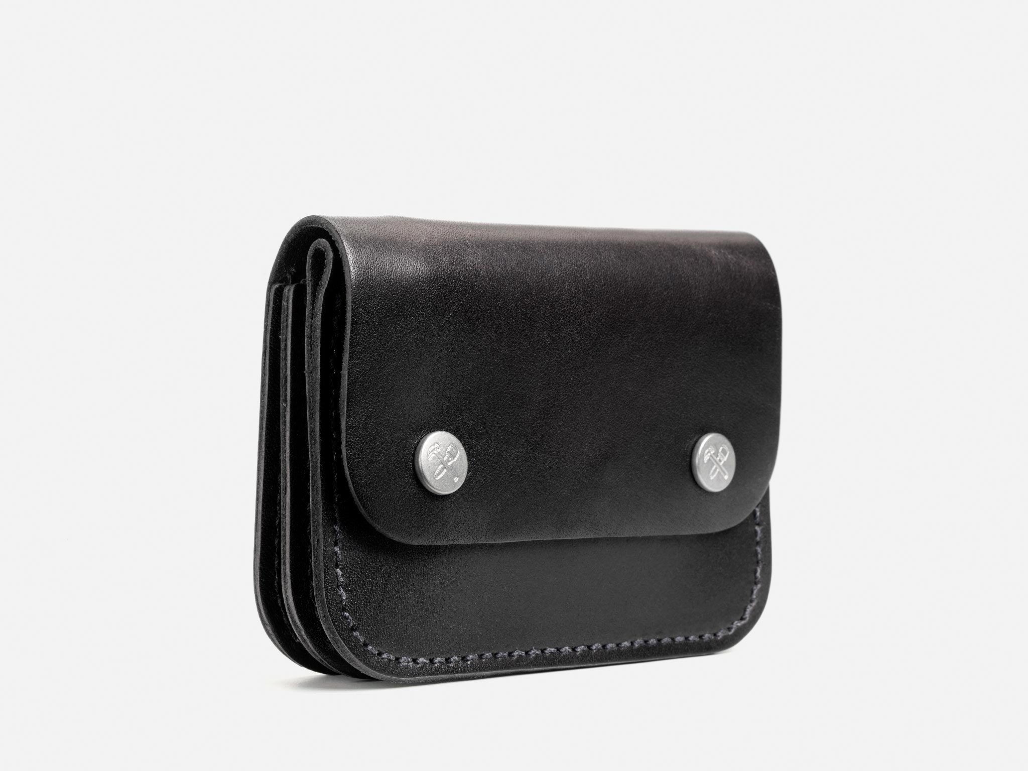 A black leather wallet with two silver snap buttons on the front, photographed against a plain light background. The wallet has a smooth finish and visible stitching along the edges.
