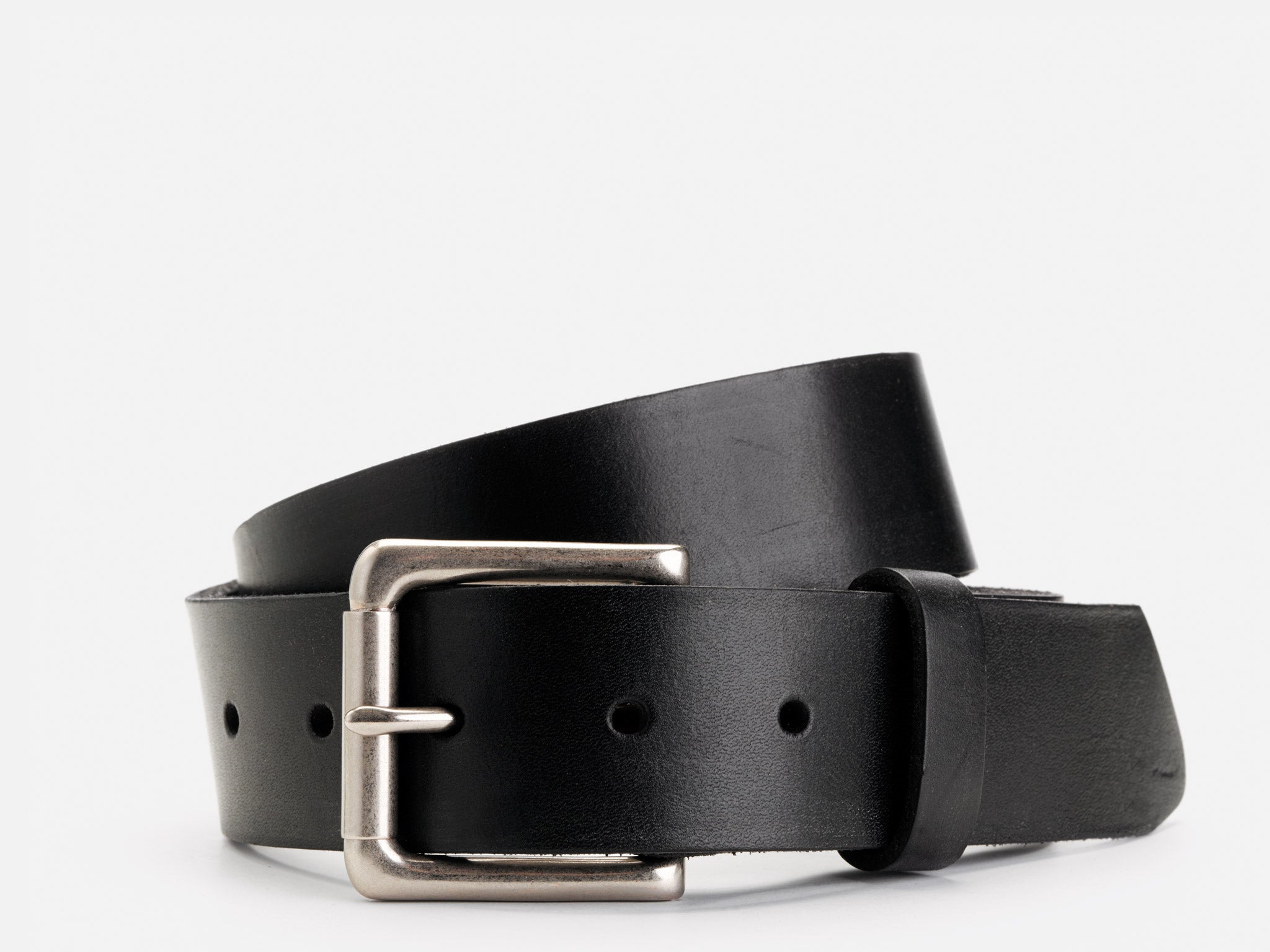 A black leather belt with a silver metal buckle is coiled in a simple loop on a plain white background.