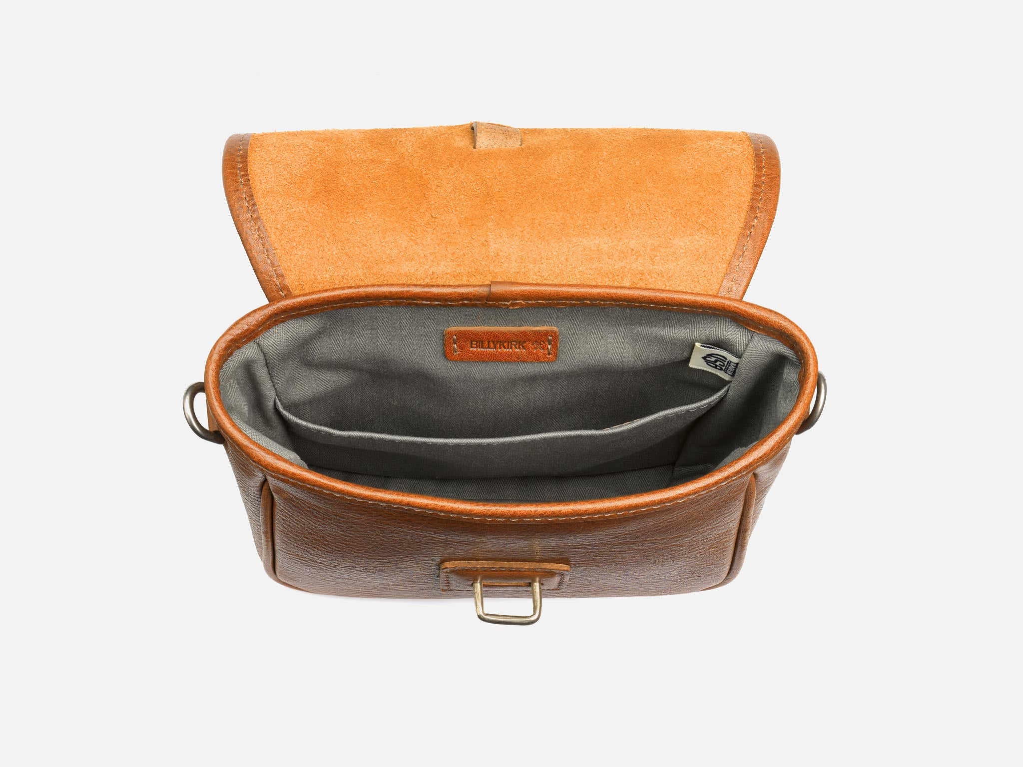 A brown leather crossbody bag with a tan suede flap, open to show a grey fabric-lined interior with two pockets and a small leather label inside.