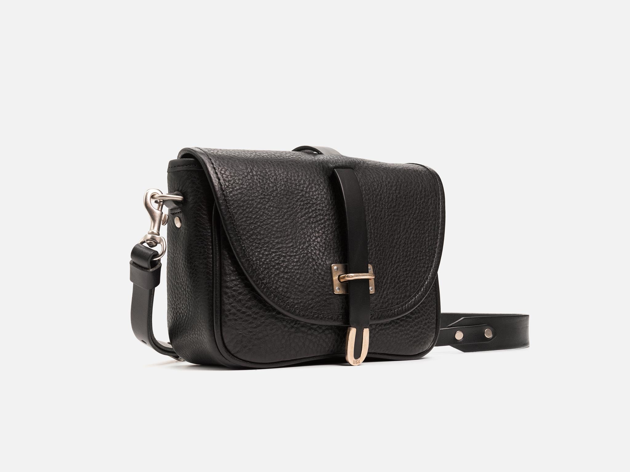 Black leather crossbody bag with a flap closure, silver hardware, pebbled texture, and an adjustable strap, photographed against a plain white background.